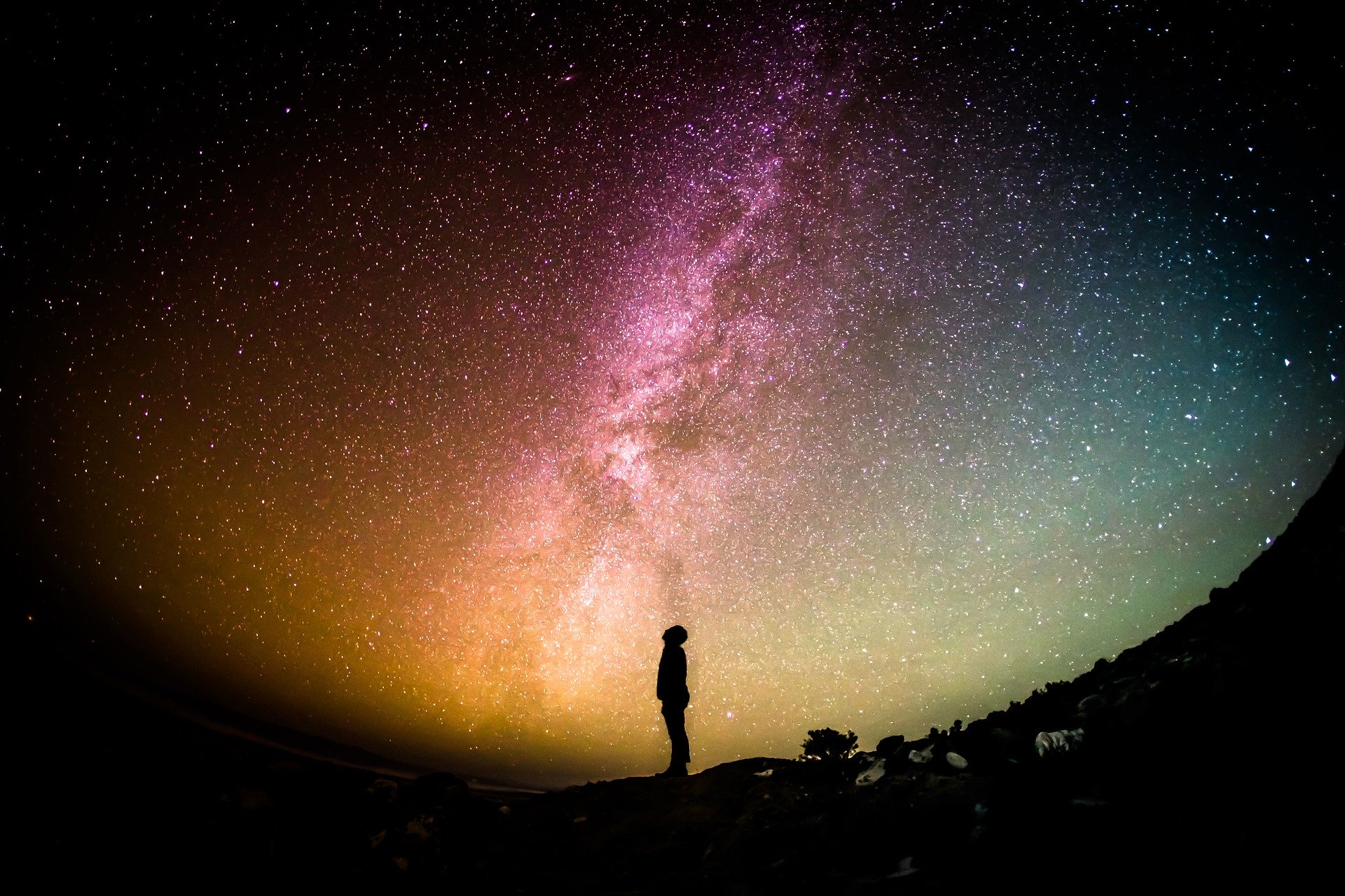 the silhoutte of a person looking up at the milky way