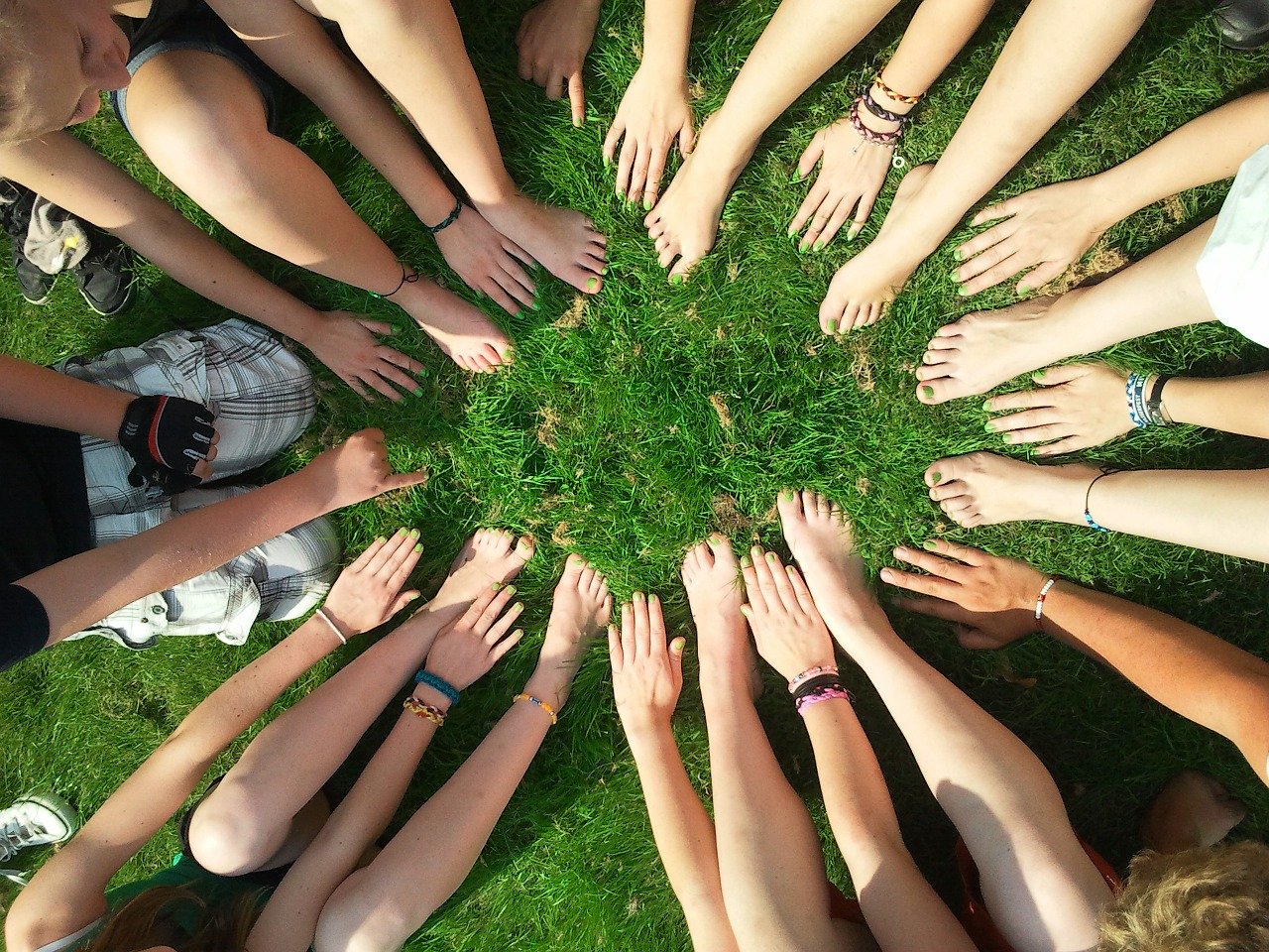 camera looking down on a group of people's bare hands and feet in a circle