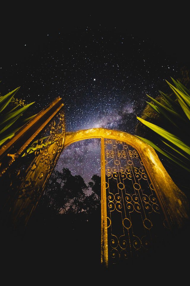 An arched gate in the darkness, with only one side open.